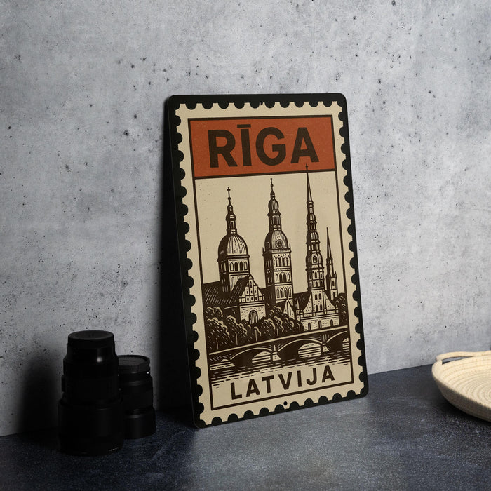 A metal sign with the word "Riga" on it, featuring an illustration of a cityscape with domes and spires.
