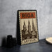 A metal sign with the word "Riga" on it, featuring an illustration of a cityscape with domes and spires.