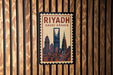 A poster of the skyline of Riyadh, Saudi Arabia, displayed on a wooden wall.