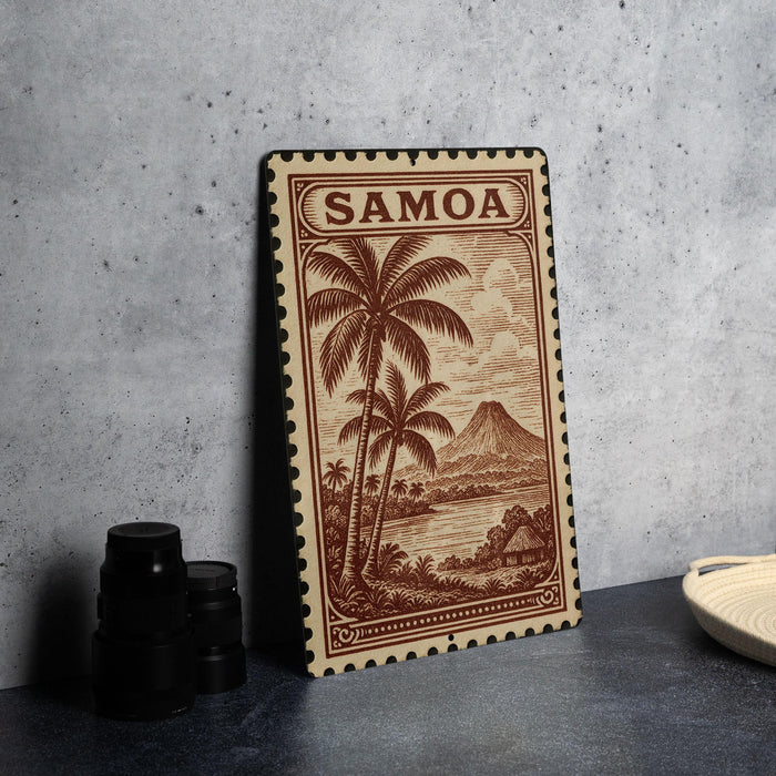 A framed stamp depicting a tropical island landscape with palm trees and a mountain, placed on a table next to some black camera lenses.