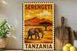 A vintage-style stamp depicting an elephant in a savanna landscape with mountains in the background, along with the text "Serengeti Tanzania".