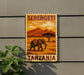 a stamp-like sign with an illustration of an elephant in a savanna landscape, along with the text "Serengeti Tanzania".