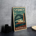 A vintage-style metal stamp depicting the Sydney Harbour Bridge and the Sydney Opera House, with the text "SYDNEY AUSTRALIA" printed on it.