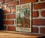A vintage postage stamp featuring the city of Vilnius, Lithuania, with a castle and other landmarks.