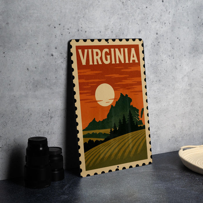 A vintage-style metal sign with the word "VIRGINIA" prominently displayed, featuring a landscape with a sunset and mountains in the background.