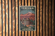 A vintage-style poster of Armenia, featuring a mountain landscape and a building, is displayed on a wooden wall.