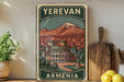 A vintage-style poster of Armenia, featuring a mountain landscape and a building, is displayed on a shelf next to a wooden cutting board and some potted plants.