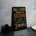 A black sign with colorful text that reads "ALL I CARE about is SKIING...and maybe 3 PEOPLE" is displayed on a table.