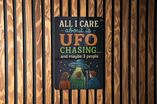 a sign with the text "All I care about is UFO chasing... and maybe 3 people" displayed on a wooden wall.