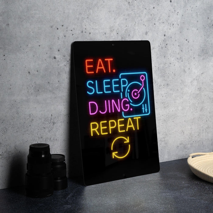 A neon sign with the text "EAT. SLEEP. DJING. REPEAT" is displayed on a black surface, accompanied by a stack of black camera lenses.