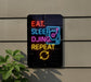 A neon sign on a wall that says "EAT. SLEEP. DJING. REPEAT" in colorful letters.