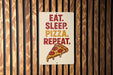 a sign with the text "EAT. SLEEP. PIZZA. REPEAT." and an illustration of a slice of pizza.