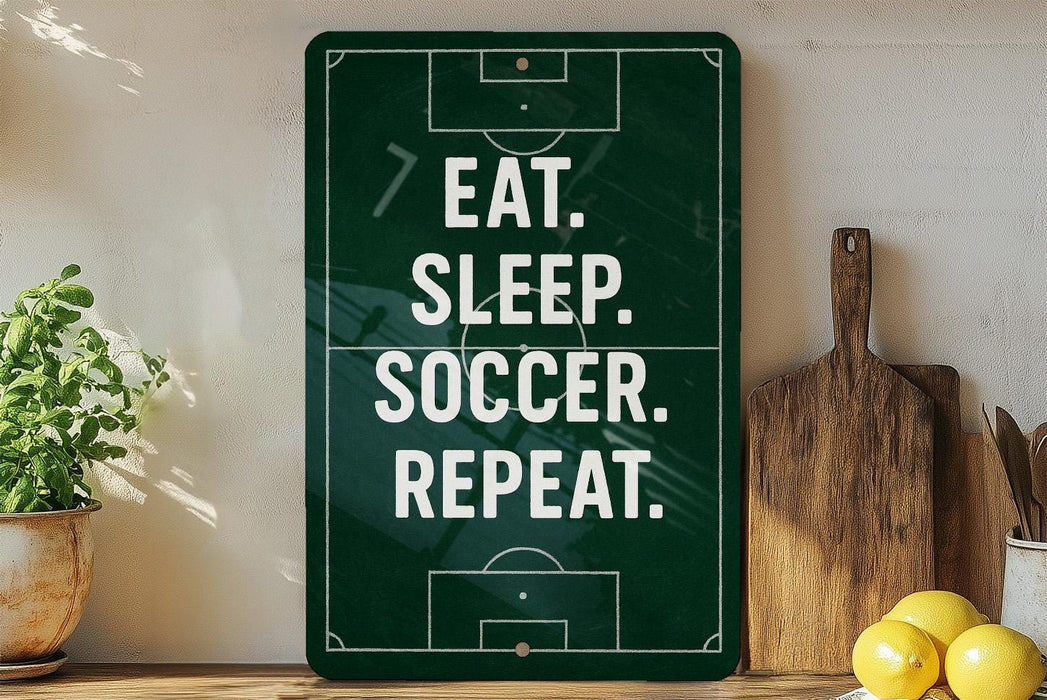 a green sign with white text that reads "EAT. SLEEP. SOCCER. REPEAT." The sign is placed on a shelf next to a wooden cutting board and a potted plant.
