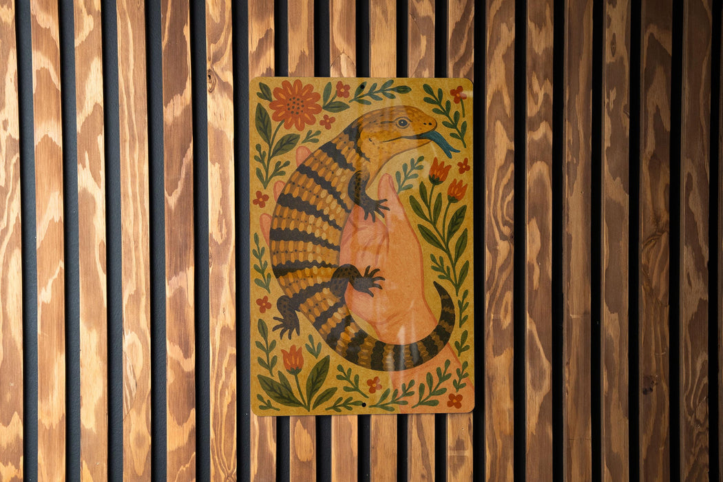 a colorful illustration of a lizard or salamander, surrounded by flowers and leaves, mounted on a wooden wall.