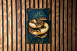 A stained glass artwork depicting a colorful snake is displayed on a wooden wall.