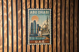 A vintage-style postage stamp from Abu Dhabi, featuring a cityscape with a mosque and a sunset in the background.