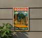 A vintage-style metal sign with a colorful illustration of Bogotá, Colombia, mounted on a wall.