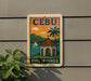 a sign that reads "Cebu Philippines" with a tropical scene depicting a building, palm trees, and a bridge.