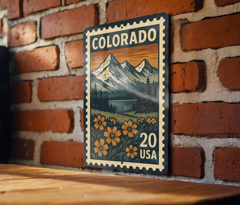 A colorful postage stamp from Colorado, featuring a mountain landscape with flowers, is displayed on a brick wall.