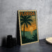 A metal stamp depicting a tropical beach scene with palm trees, a sunset, and a body of water.