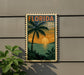 A vintage-style postage stamp depicting a tropical beach scene with palm trees, a sunset, and a body of water.