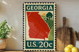 A vintage-style metal stamp with a red state of Georgia on it, placed on a wooden surface next to a wooden cutting board and some lemons.