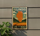 A vintage-style metal sign with the text "ILLINOIS" and "LAND OF LINCOLN" is displayed on a wall, featuring an illustration of a state map and a rural landscape.