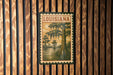 A vintage-style postage stamp depicting a scene from Louisiana, featuring a tree with hanging roots and a body of water.