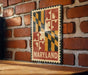 A metal sign with the word "MARYLAND" displayed on it, mounted on a brick wall.