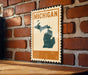 A vintage-style metal sign with the word "MICHIGAN" printed on it, mounted on a brick wall.