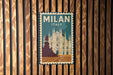 A vintage-style poster of the Milan Cathedral, a famous landmark in Italy, is displayed on a wooden wall.