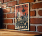 A vintage-style metal sign featuring the city of Montreal, Canada, with a maple leaf and a bridge in the background.
