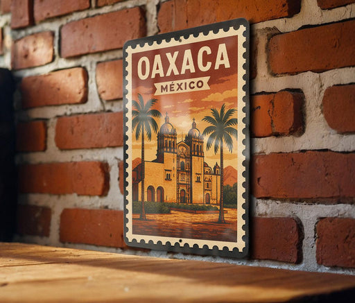A vintage-style poster of Oaxaca, Mexico, featuring a brick wall and palm trees, is displayed on a wooden surface.