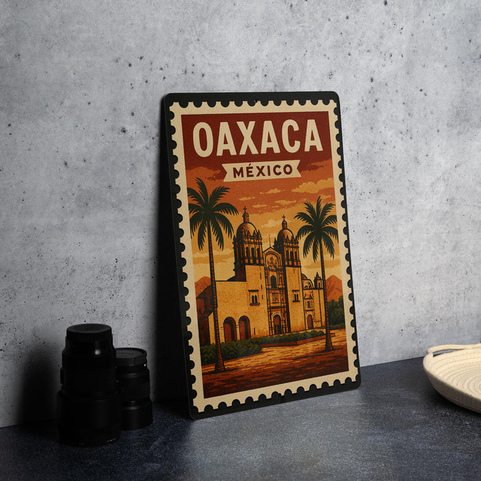 A vintage-style metal stamp depicting the Oaxaca Cathedral in Mexico, with palm trees and a warm sunset in the background.