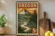 A vintage-style metal sign with a mountain landscape and a river, featuring the word "OREGON" prominently displayed.