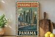 A framed poster of Panama City, featuring a cityscape with tall buildings and a bridge, is displayed on a wall next to a wooden cutting board and some potted plants.