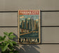 A vintage-style metal sign with a cityscape illustration and the text "Panama City Panama" is displayed on a wall.