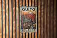A metal sign with a colorful illustration of a cityscape and a mountain, mounted on a wooden wall.