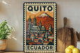 A vintage-style metal sign with a colorful illustration of a cityscape and a mountain, displaying the text "QUITO ECUADOR".