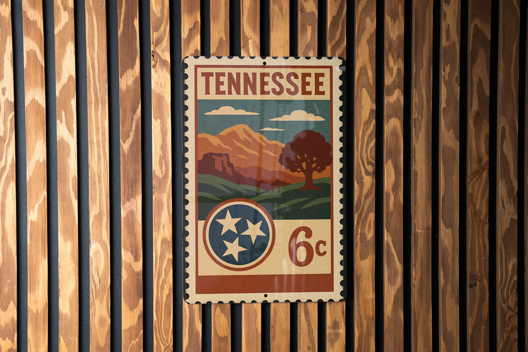 A vintage-style postage stamp from Tennessee, featuring a mountain landscape and a tree, is displayed on a wooden wall.