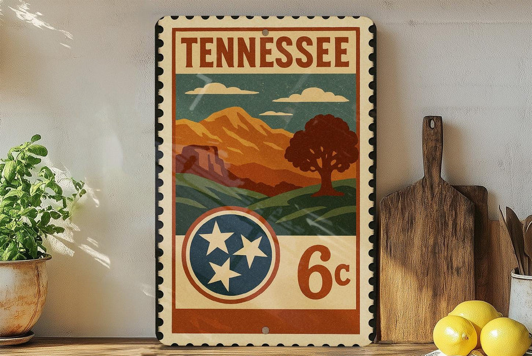 A vintage-style metal sign with the text "TENNESSEE" and a landscape illustration, featuring mountains, trees, and a pine tree.