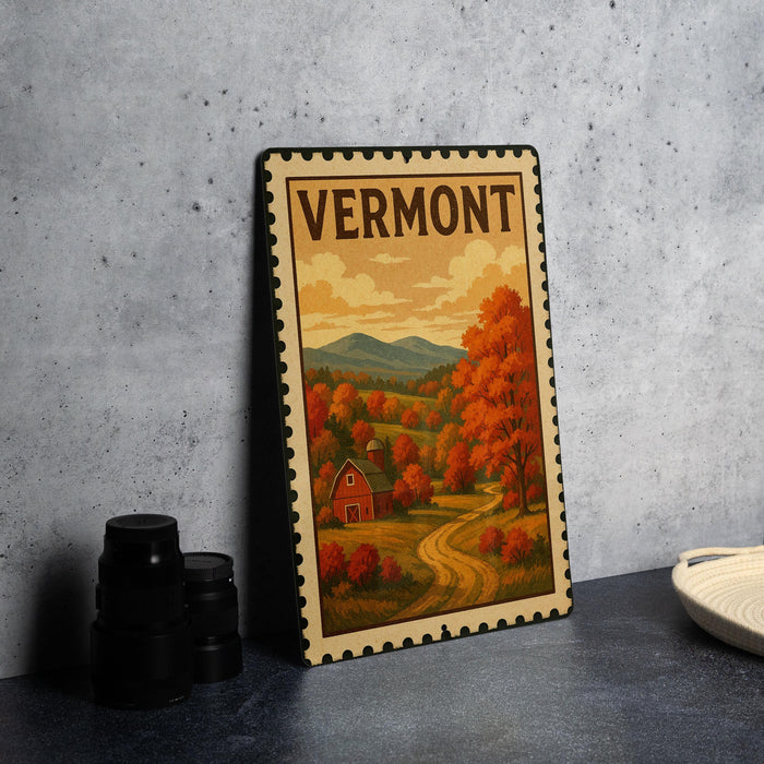 A framed vintage postage stamp depicting a scenic autumn landscape in Vermont, with a red barn and a winding road in the foreground.