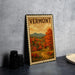 A framed vintage postage stamp depicting a scenic autumn landscape in Vermont, with a red barn and a winding road in the foreground.