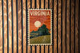 A vintage-style postage stamp depicting a scenic landscape with mountains, trees, and a sunset, hanging on a wooden wall.