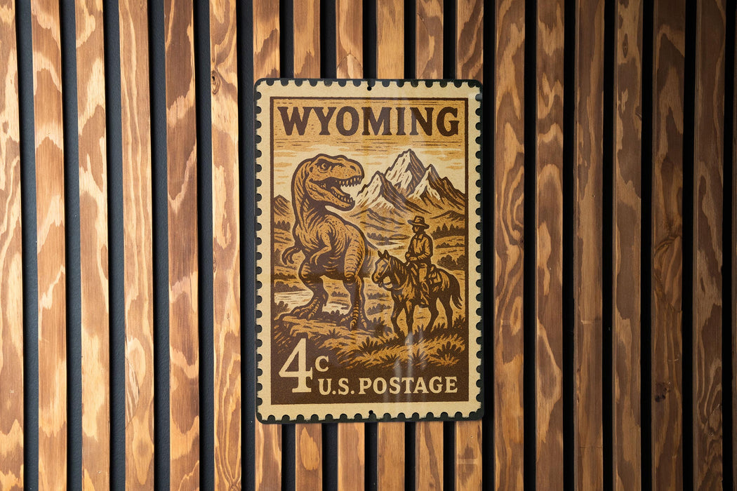 A Wyoming postage stamp featuring a dinosaur and a cowboy on horseback, mounted on a wooden wall.