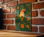 A colorful parrot is depicted on a decorative green and gold frame, set against a brick wall.