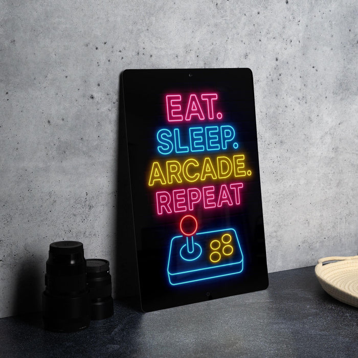A neon sign with the text "EAT. SLEEP. ARCAKE. REPEAT" in neon colors is displayed on a black surface, with a video game controller visible below it.