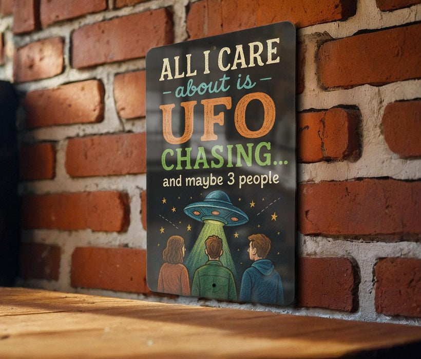 a sign with the text "All I care about is UFO chasing... and maybe 3 people" against a brick wall background.