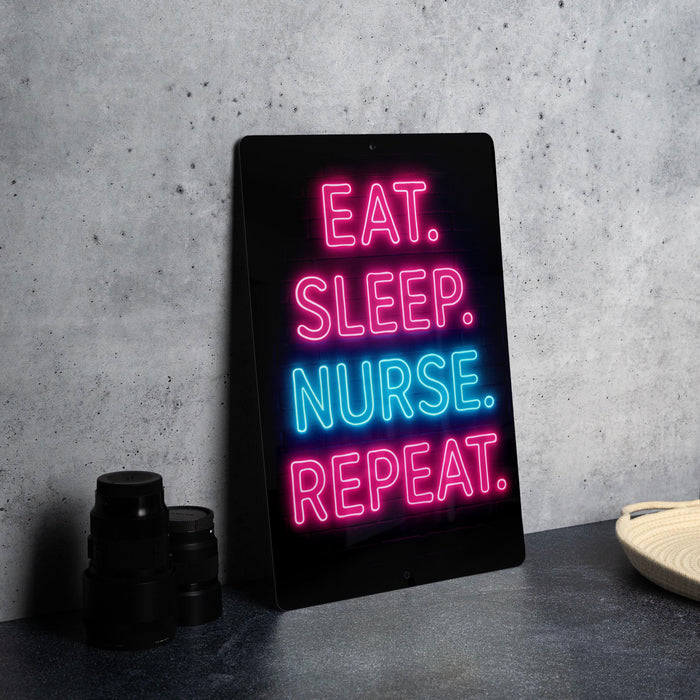 A neon sign with the text "EAT. SLEEP. NURSE. repeating." in pink and blue neon lights is displayed on a black surface.