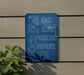 a blue sign with white text that reads "EAT. SLEEP. PUZZLES. REPEAT." The sign is mounted on a wall, and there is a plant to the left of the sign.